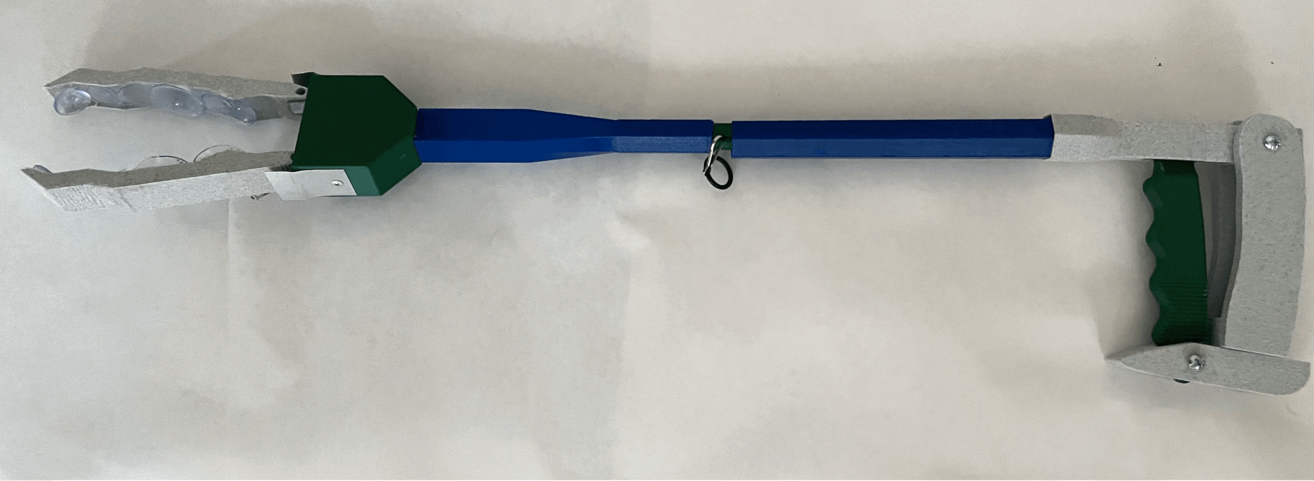 3D-printed prototype of a reacher-grabber product. It is long, thin, and made out of dark green, navy blue, and grey 3D printed plastic.